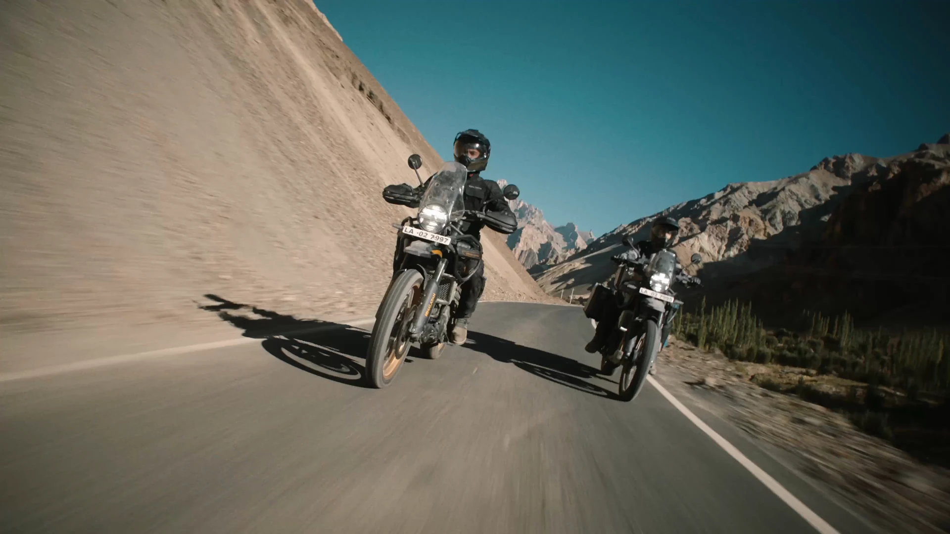 Dva jezdci na Royal Enfield Himalayan na horské silnici – z dodaného filmu